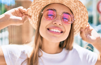 smiling girl in pink glasses and hat