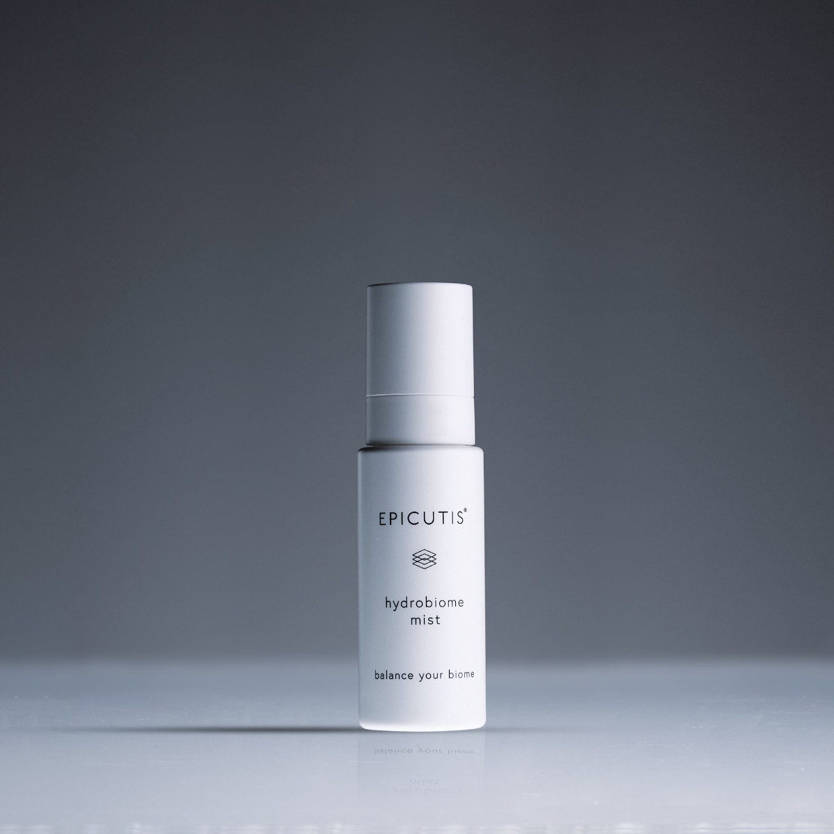 A white bottle labeled "Epicutis Hydrobome Mist" stands on a reflective surface against a plain gray background.