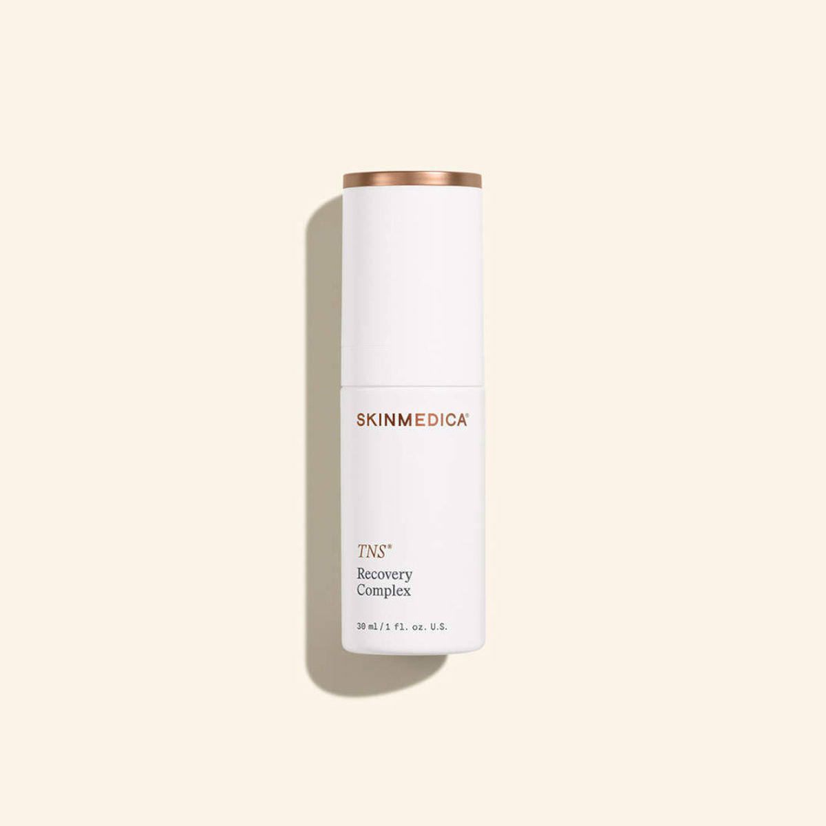 A white bottle of SkinMedica TNS Recovery Complex with a copper-colored cap, shown upright against a beige background.